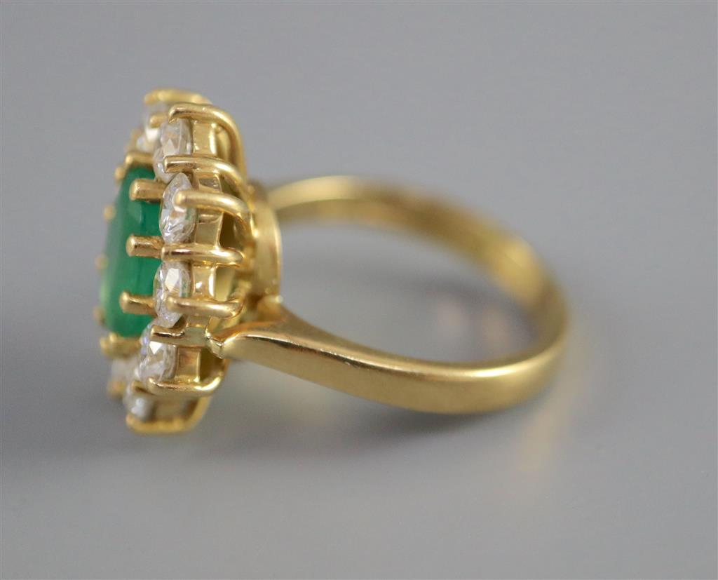 A modern 18ct gold, emerald and diamond oval cluster ring,